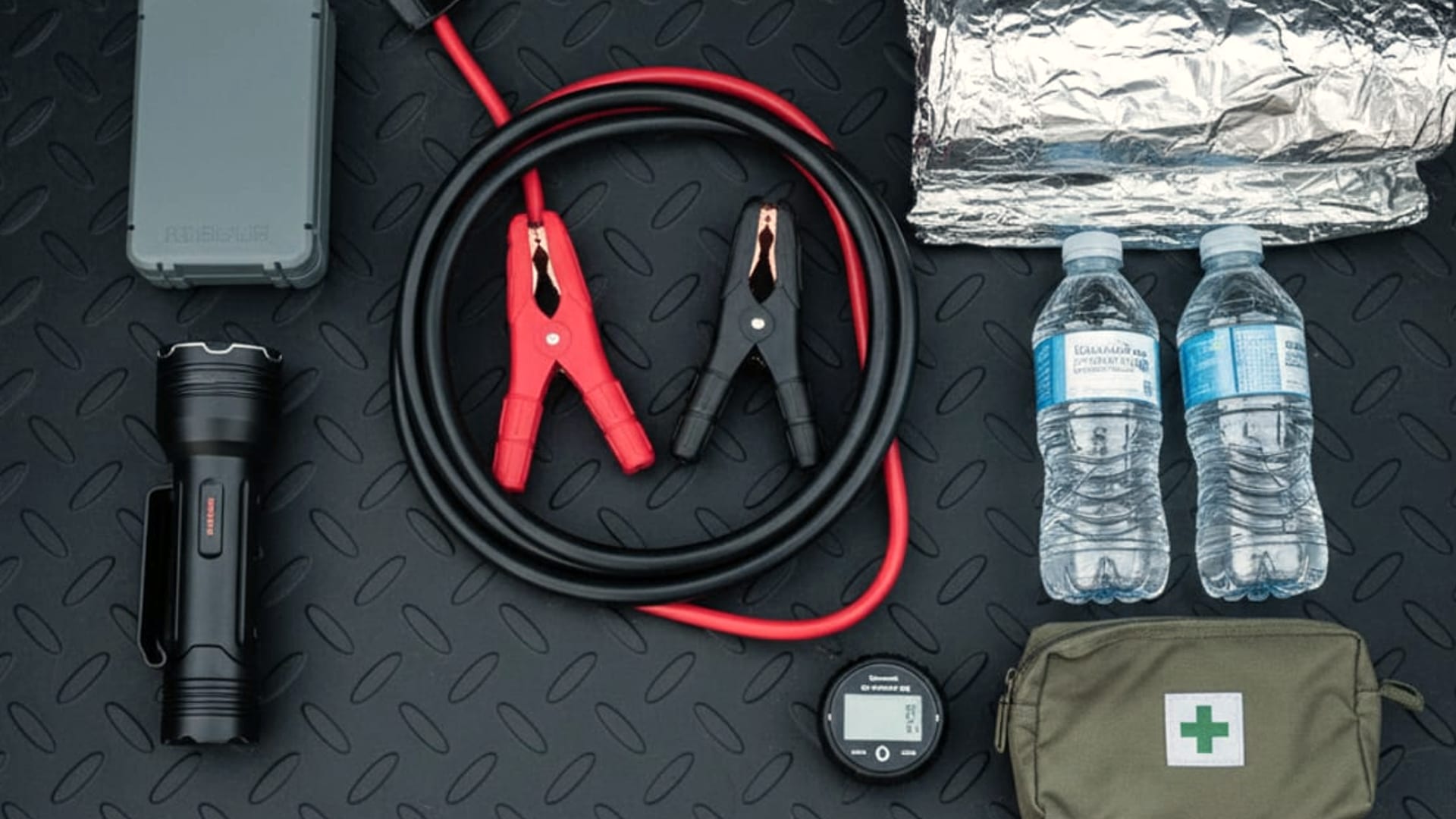 Overhead view of tow equipment laid out flat, including soft-strap wheel nets, a jump pack, a winch hook, jumper cables, and a clipboard with service forms